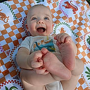 Ezra joined the competition — help win amazing prizes! baby, smiling, feet, hand, blanket, pattern, outdoor, grass, child, happy, cute, infant, playful, clothing, person, skin, blue_eyes, toddler, nature, lying_down