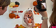 Blake joined the competition — help win amazing prizes! adult, autumn_leaves, baby, camera, candid, chair, child, cute, fall_decor, hands, happy, headband, indoor, orange_outfit, person, photography, pumpkin, smile, studio, white_background