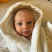 Blake is registered to the contest to win money with this photo: baby, blanket, child, cozy, cute, eyes, face, head, hood, indoors, infant, person, portrait, skin, smile, soft_texture, towel, warm_light, white, young