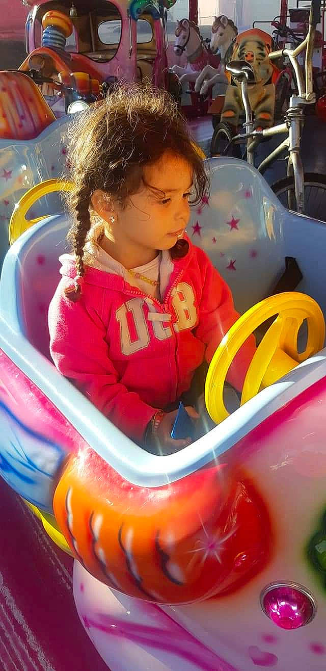 Kenza participe au concours pour gagner de l'argent avec cette photo : amusement_ride, automotive_design, automotive_wheel_system, baby_products, child, city, fun, happy, inflatable, leisure, motor_vehicle, outdoor_play_equipment, person, personal_protective_equipment, play, playground, recreation, sitting, steering_wheel, toddler