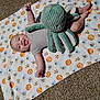 baby, smiling, blanket, plush_toy, octopus, carpet, infant, happy, child, cute, animal_pattern, soft_toy, lying_down, indoors, playtime, one_person, clothing, gray_shirt, small_child, toddler
