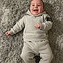 baby, barefoot, carpet, child, clothing, cozy, cute, happy, hoodie, indoor, infant, lying_down, portrait, relaxed, shag_rug, smiling, sweatpants, sweatshirt, toddler, young_child