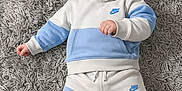 Marsh is registered to the contest to win money with this photo: baby, barefoot, blue_clothing, casual_wear, child, cute, fashion, fluffy, happy, hoodie, indoor, infant, lying_down, nike, pants, playful, portrait, rug, smiling, white_clothing