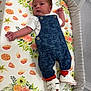 Marsh is registered to the contest to win money with this photo: baby, infant, overalls, blue_clothing, red_socks, white_shoes, floral_pattern, bassinet, crib, newborn, cute, sleeping_area, fabric, pattern, child, small, lying_down, indoors, soft, peaceful