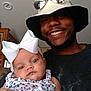 baby, bow, child, smile, man, hat, sunglasses, indoor, portrait, person, clothing, happy, face, holding, flower_pattern, headwear, family, casual, cute, infant