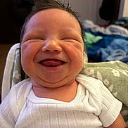 Tatum is registered to the contest to win money with this photo: baby, smiling, happy, infant, face, hair, white_shirt, blanket, cute, expression, indoors, person, child, newborn, portrait, skin, chubby_cheeks, tongue_out, cozy, casual