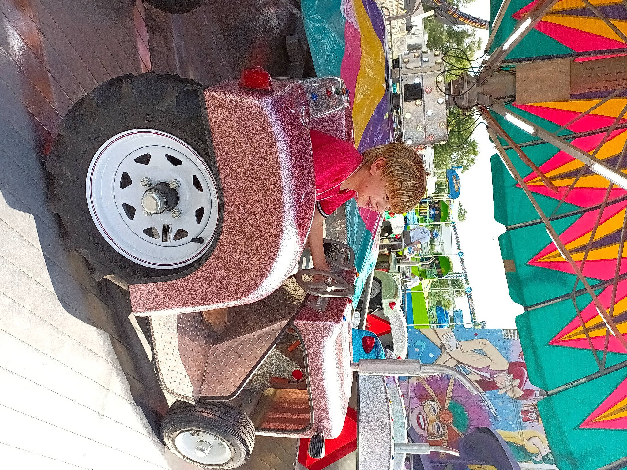 Colin is registered to the contest to win money with this photo: art, auto_part, automotive_exterior, automotive_tire, automotive_wheel_system, car, city, event, fun, hubcap, leisure, machine, magenta, motor_vehicle, person, synthetic_rubber, tire, tire_care, tread, vehicle