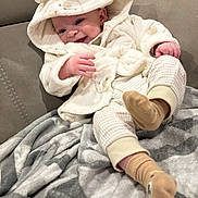 Tommy joined the competition — help win amazing prizes! baby, infant, smiling, hoodie, bear_ears, blanket, soft_fabric, cozy, socks, plaid_pants, cute, happy, child, portrait, indoor, couch, comfort, warm_clothing, relaxed, playful