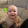 Tommy joined the competition — help win amazing prizes! baby, child, smiling, onesie, indoor, couch, toy, hair_clip, happy, face, infant, person, sitting, dimples, living_room, plush_blanket, cute, young_child, home, playtime
