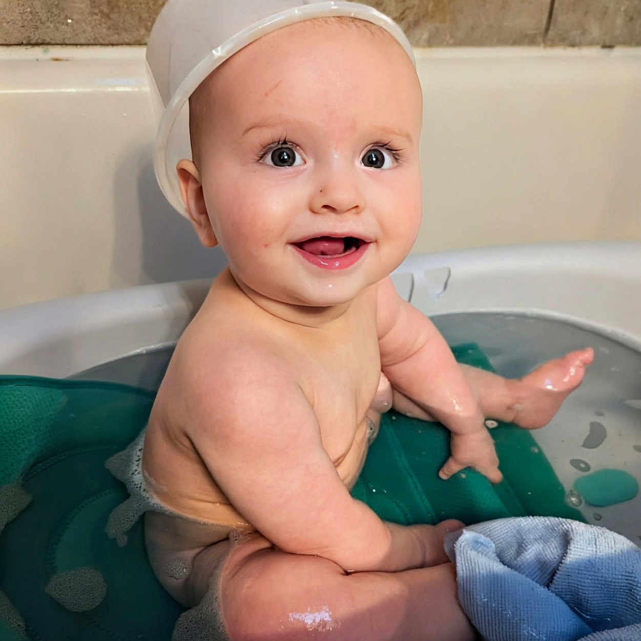 Jd is registered to the contest to win money with this photo: baby, bathtub, water, smile, child, playful, washcloth, cap, sitting, skin, cute, happy, bath, indoors, toddler, fun, face, expression, clean, splash