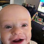 Owen joined the competition — help win amazing prizes! baby, close_up, smile, happy, face, child, indoor, television, blurred_background, expression, cute, joyful, infant, person, head, mouth, eyes, skin, clothing, home