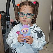 Mya a rejoint le concours — aidez-le/la à gagner de superbes lots ! child, glasses, toy, plush_toy, indoor, vacuum_cleaner, mickey_mouse, minnie_mouse, pajamas, hair_ties, floor_tiles, door, sweatshirt, pants, person, face, hand, expressionless, standing, home