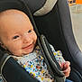baby, smile, car_seat, child, clothing, safety_harness, infant, cute, happy, face, person, seat, fabric, pattern, hand, indoor, portrait, young_child, head, apparel