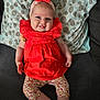 baby, infant, smiling, orange_dress, headband, bow, polka_dot, pillow, couch, patterned_clothing, cute, tongue_out, happy, child, indoor, person, young_child, sitting, playful, fabric