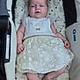 baby, infant, stroller, dress, lace, headband, flower, footwear, shoe, cute, sleepy, cushion, teddy_bear_pattern, child, person, indoors, soft_toys, fabric, skin, hand