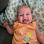 baby, infant, smiling, tongue_out, orange_clothing, minnie_mouse, cartoon_character, polka_dot_blanket, couch, happy, cute, child, playful, indoors, fabric, pattern, sleeveless, person, young, resting