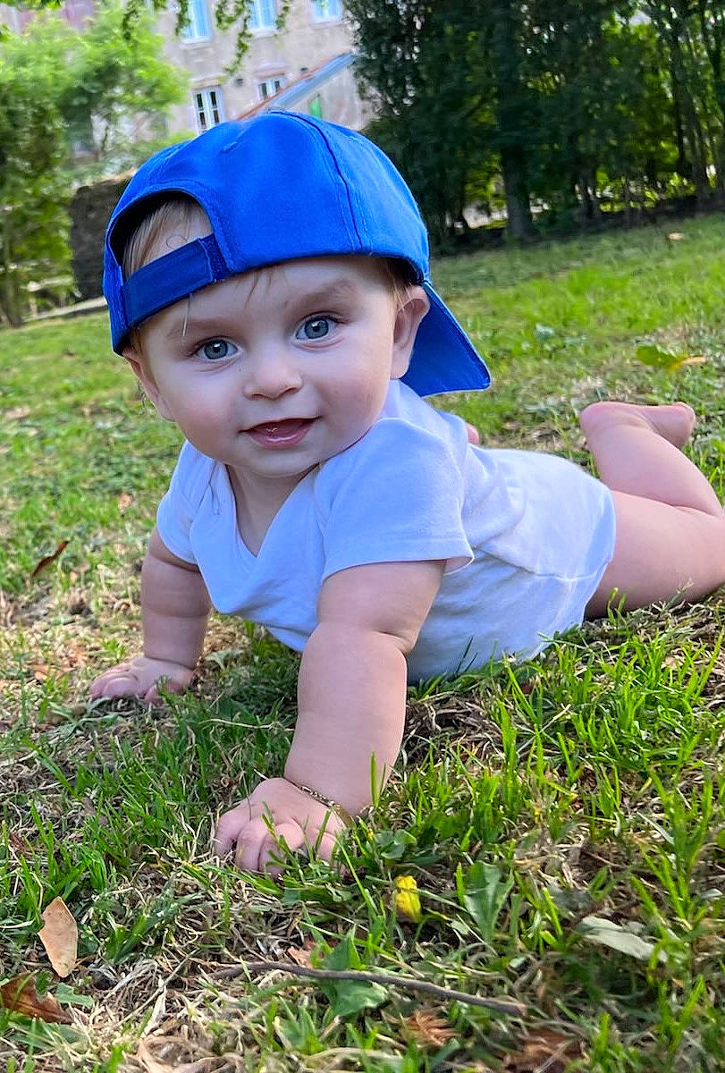 James a rejoint le concours — aidez-le/la à gagner de superbes lots ! baby, baby_toddler_clothing, baseball_cap, blue, cap, electric_blue, fashion_accessory, fun, grass, grassland, happy, headwear, lawn, leaf, leisure, meadow, people_in_nature, person, plant, recreation