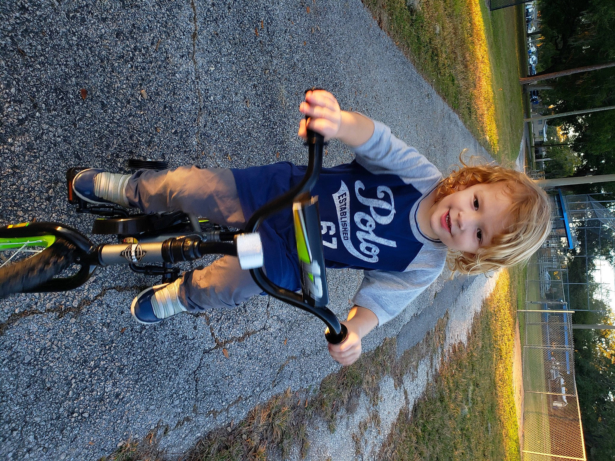 Khallin is registered to the contest to win money with this photo: adventure, asphalt, bicycle_handlebar, child, city, cool, fun, grass, hairstyle, happy, joy, leisure, person, personal_protective_equipment, plant, recreation, shadow, t_shirt, toddler, tree