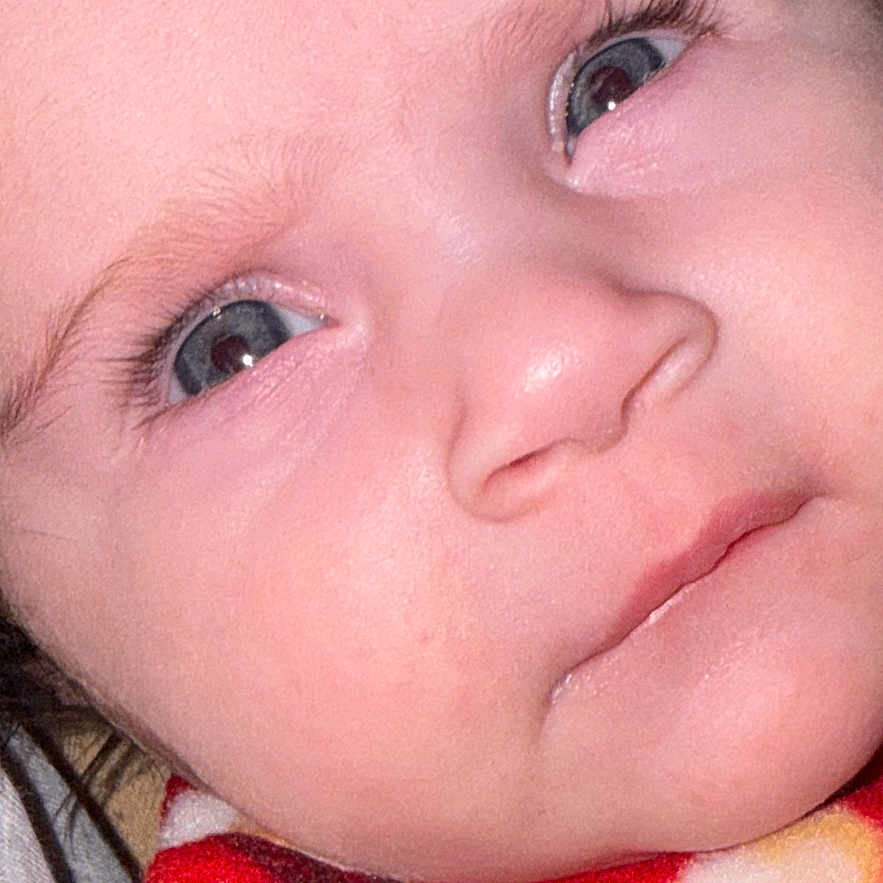 Mila Elysa participe au concours pour gagner de l'argent avec cette photo : baby, blanket, blue_eyes, child, close_up, cute, expression, eyelashes, face, head, infant, newborn, person, portrait, red, skin, soft, warm, yellow, young