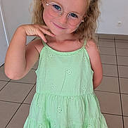 Romy a rejoint le concours — aidez-le/la à gagner de superbes lots ! casual, child, curly_hair, cute, fashion, flower_hair_accessory, footwear, girl, glasses, green_dress, happy, indoor, person, pigtails, playful, portrait, pose, smiling, tile_floor, young