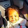 baby, child, car_seat, pacifier, sunlight, curly_hair, smile, infant, clothing, clip, pink, seatbelt, safety, cute, portrait, indoors, happy, person, young_child, toddler