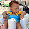 Miyori is registered to the contest to win money with this photo: baby, child, infant, beach, swimsuit, yellow_bows, inflatable_chair, teddy_bear_pattern, curly_hair, tongue_out, summer, sunny, outdoor, sand, umbrella, people, relaxation, vacation, playful, cute
