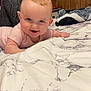 Bellamy is registered to the contest to win money with this photo: baby, smiling, bed, blanket, wood_paneling, infant, face, person, indoor, resting, happy, cute, crawling, child, young, marble_pattern, fabric, cozy, home, portrait