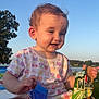 toddler, child, outdoor, sunlight, smiling, shirt, colorful_clothing, cardboard, lake, trees, nature, grass, happy, playful, baby, shorts, sitting, daylight, sky, cute