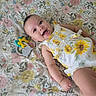 Amina joined the competition — help win amazing prizes! baby, infant, smiling, crib, floral_pattern, dress, sunflower, toy, teething_toy, happy, lying_down, child, cute, indoor, colorful, playful, person, face, skin, small