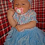 Kamilla is registered to the contest to win money with this photo: baby, pacifier, blue_dress, headband, bow, floral_pattern, blanket, red_checkered, sleeping, infant, cute, child, clothing, hand, face, portrait, lying_down, indoors, soft_texture, cozy