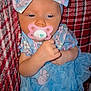 Kamilla is registered to the contest to win money with this photo: baby, pacifier, bow, blue_dress, floral_pattern, infant, closeup, face, headwear, sleepy, blanket, plaid, couch, hand, cute, indoors, child, soft, portrait, resting