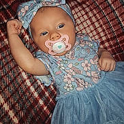 Kamilla joined the competition — help win amazing prizes! baby, infant, child, pacifier, headband, bow, blue_dress, floral_pattern, blanket, plaid, lying_down, raised_arm, cute, adorable, face, eyes, hand, skin, indoors, person