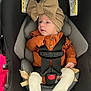 baby, car_seat, child, infant, hat, bow, orange_clothing, straps, seatbelt, legs, white_socks, ribbons, cute, indoor, safety, young_child, person, portrait, newborn, cozy