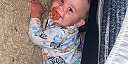 Porter is registered to the contest to win money with this photo: baby, child, pajamas, pacifier, toy, carpet, floor, bed_frame, smiling, indoors, footwear, sole, person, cute, lying_down, sleepwear, infant, face, hand, home
