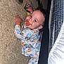 baby, child, pajamas, pacifier, toy, carpet, floor, bed_frame, smiling, indoors, footwear, sole, person, cute, lying_down, sleepwear, infant, face, hand, home