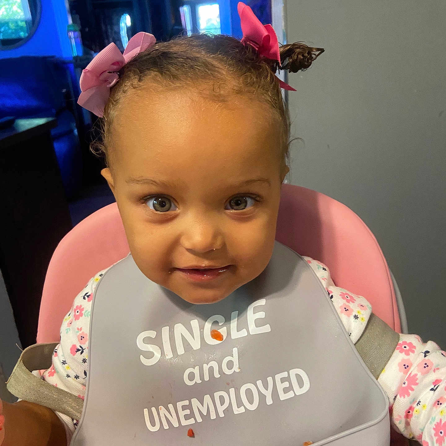 Melody joined the competition — help win amazing prizes! baby, child, infant, high_chair, bib, pink, bows, hair_bows, floral_clothing, smiling, portrait, indoor, kitchen, seated, face, eyes, food, snack, funny_bib, 家庭