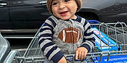 Ezekiel is registered to the contest to win money with this photo: blue_handle, box_of_goods, car, child, football_patch, gray_clothing, grocery_store, hands, happy_face, hat_with_ears, knit_hat, onesie, parking_lot, safety_belt, seat, shopping_cart, smiling, striped_sleeves, suv, toddler