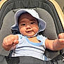 baby, child, hat, onesie, smiling, fists, stroller, cushion, infant, portrait, happy, cute, indoor, clothing, headwear, person, seat, babywear, babyhat, expression