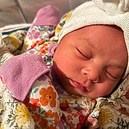 Selena is registered to the contest to win money with this photo: newborn, baby, sleeping, hat, blanket, floral_pajamas, cozy, soft, peaceful, infant, face, closeup, cute, resting, child, warm, comfort, portrait, indoors, sleep