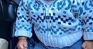 Krystian is registered to the contest to win money with this photo: baby, child, car_seat, blue_hat, knitwear, sweater, patterned_clothing, blue_pants, socks, infant, portrait, serious_expression, indoors, seatbelt, cute, young_child, clothing, person, closeup, casual