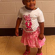 Rhyani joined the competition — help win amazing prizes! toddler, girl, child, smiling, standing, pink_skirt, white_tshirt, pigtails, beads, indoor, tile_floor, brick_wall, shoes, happy, cute, fashion, portrait, person, young_child, casual_clothing