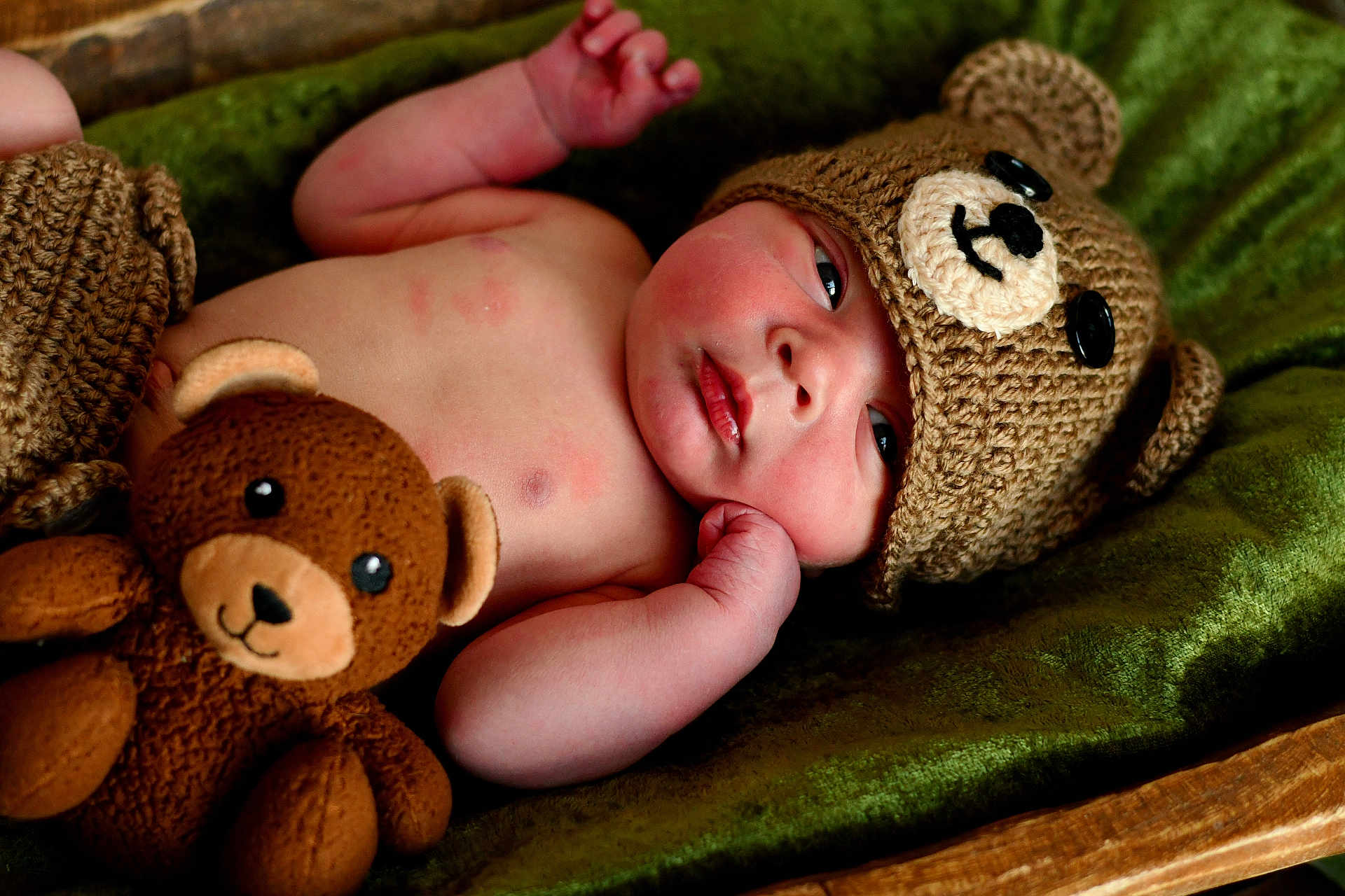 Dexter joined the competition — help win amazing prizes! baby, infant, knitted_hat, bear_hat, plush_toy, stuffed_animal, green_blanket, soft_texture, cute, child, newborn, sleepwear, relaxing, indoors, portrait, closeup, hand, face, expression, resting