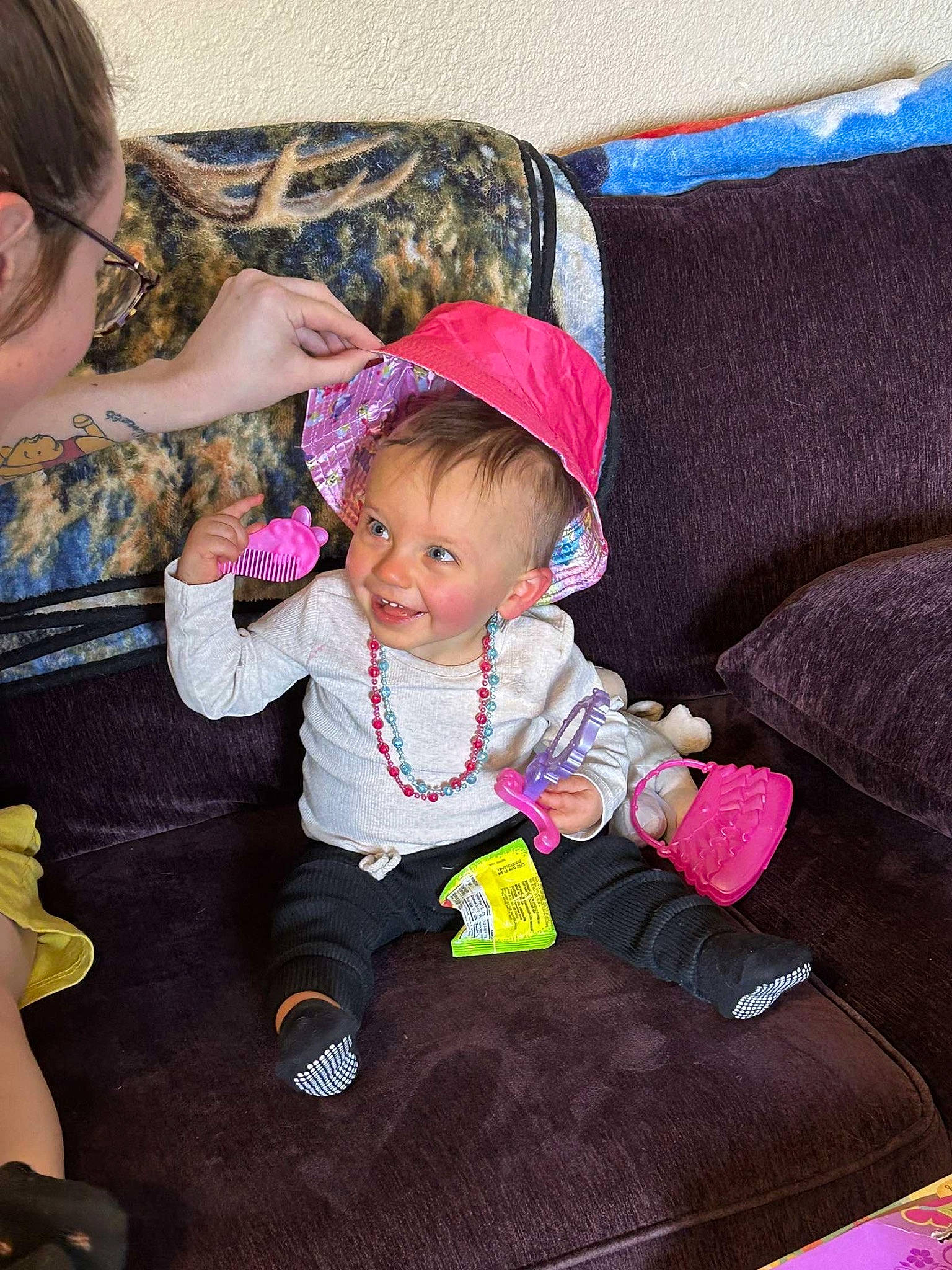 Wynter is registered to the contest to win money with this photo: baby, baby_toddler_clothing, child, comfort, couch, fashion_accessory, fun, happy, hat, joy, lap, magenta, person, pink, product, purple, room, sitting, skin, smile