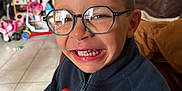 Emilio participe au concours pour gagner de l'argent avec cette photo : child, clothing, couch, face, floor, glasses, hair, hand, happy, home, indoor, jacket, living_room, lollipop, person, playful, reflection, smile, toy, young