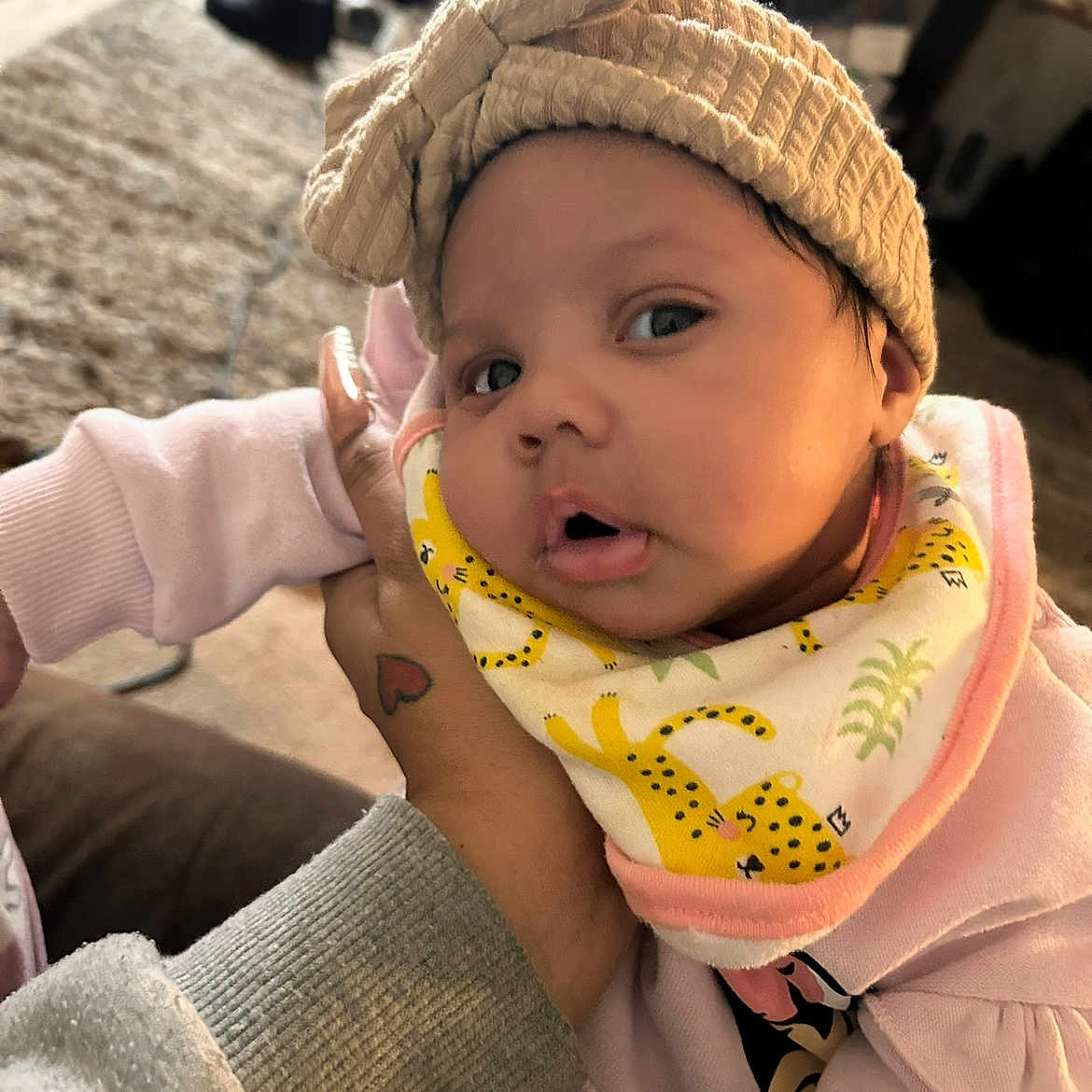 Kahmiaya is registered to the contest to win money with this photo: baby, bib, blurred_background, bow, carpet, cheetah_pattern, child, cute, eyes, face, hand, headband, heart_tattoo, indoor, infant, mouth, person, pink_clothing, soft_lighting, tattoo