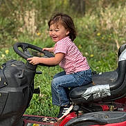 Rosalynn joined the competition — help win amazing prizes! child, toddler, smiling, pink_shirt, jeans, ride_on_mower, steering_wheel, outdoor, grass, nature, play, happy, casual_clothing, seat, black_shoes, greenery, daylight, fun, young_child, playtime