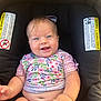 baby, smiling, blue_eyes, car_seat, floral_shirt, infant, cute, child, seat, warning_labels, happy, skin, hand, mouth, cheeks, clothing, person, indoors, sitting, young_child