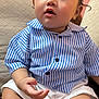 baby, child, clothing, couch, curious, cute, expression, face, furniture, hair, hand, indoor, legs, person, portrait, sitting, skin, striped_shirt, white_shorts, young_child