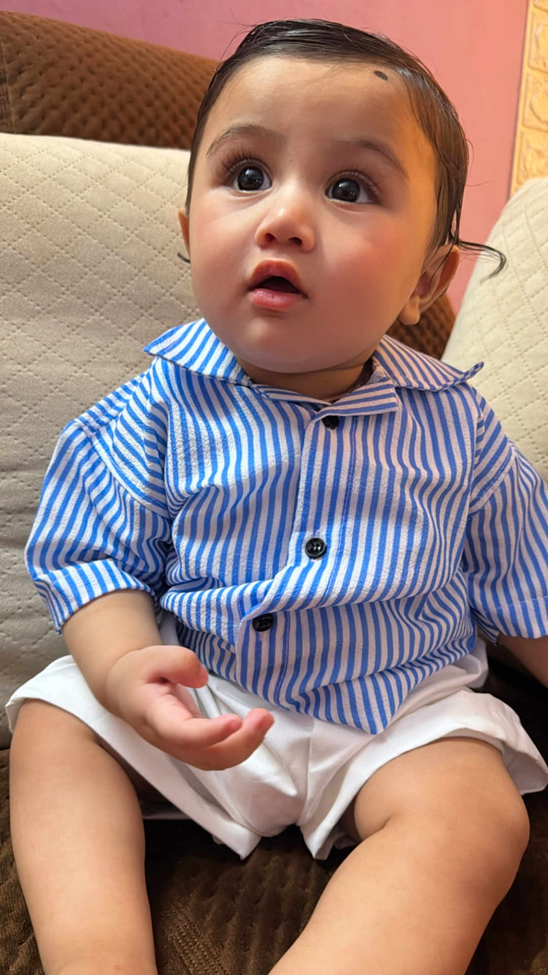 Manvay is registered to the contest to win money with this photo: baby, child, clothing, couch, curious, cute, expression, face, furniture, hair, hand, indoor, legs, person, portrait, sitting, skin, striped_shirt, white_shorts, young_child
