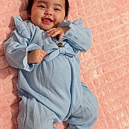 Amaya joined the competition — help win amazing prizes! baby, bedroom, blanket, blue_outfit, bow, cheeks, cozy, cute, hair, hand, happy, infant, lying_down, onesie, pink_blanket, playful, portrait, ruffles, smile, toes